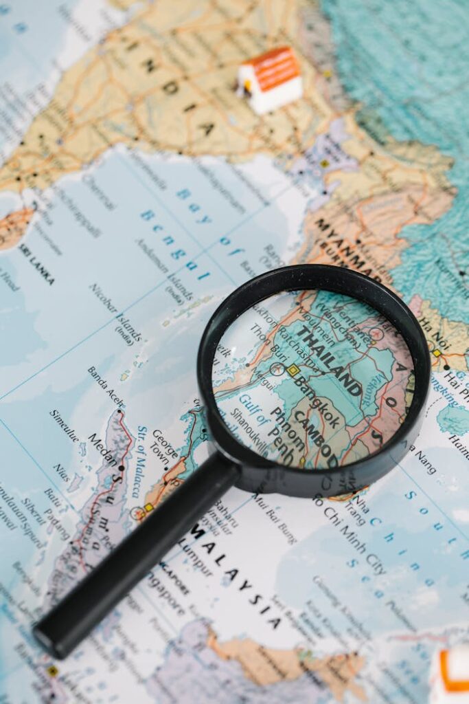 A magnifying glass highlighting Thailand on a detailed world map, ideal for travel-themed visuals.